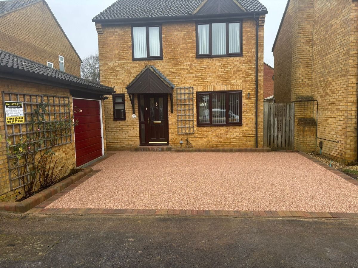 Front view of a two-story brick house with a red garage door and gravel driveway