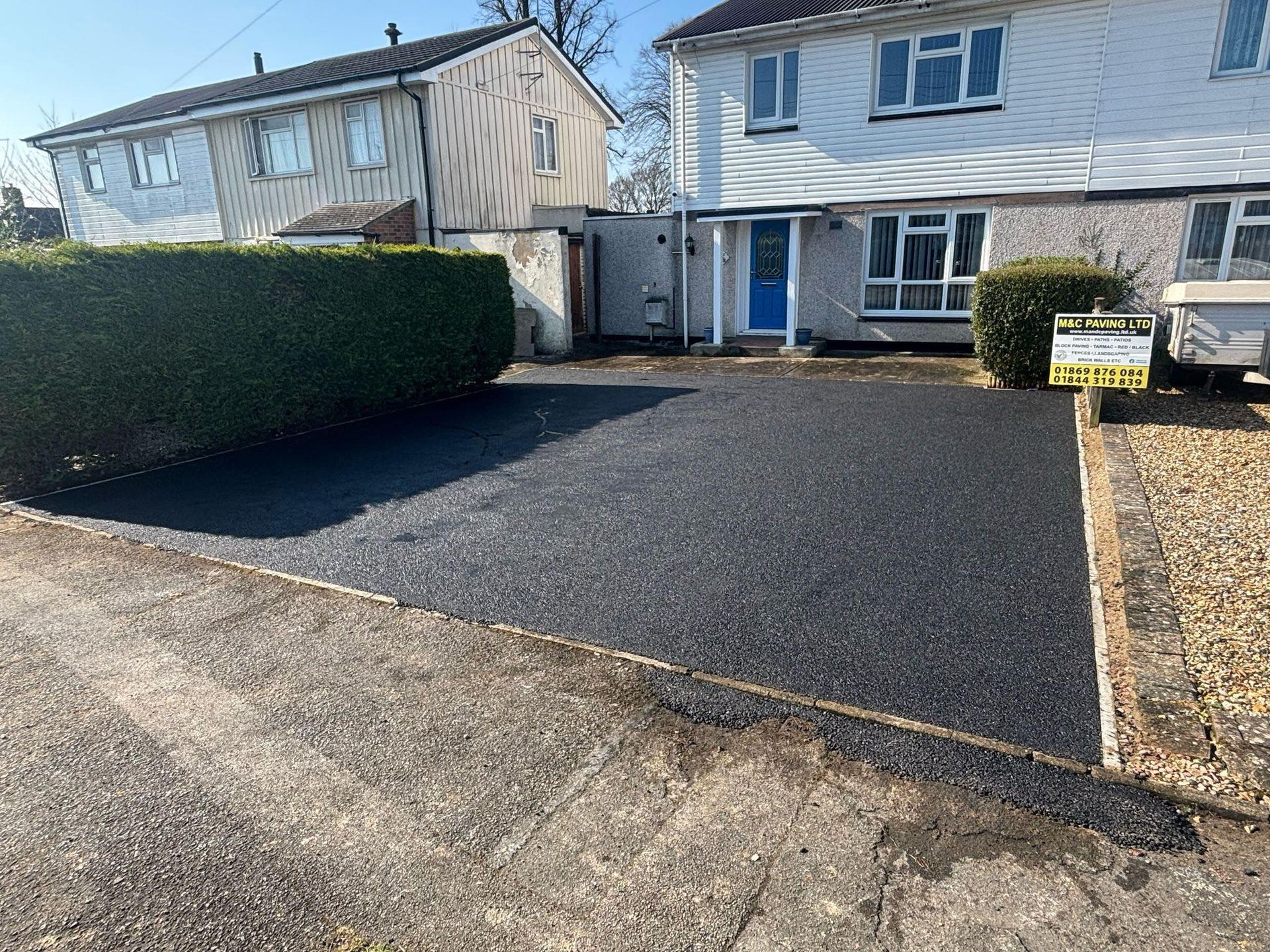Semi-detached house with a newly paved driveway and trimmed hedges in front