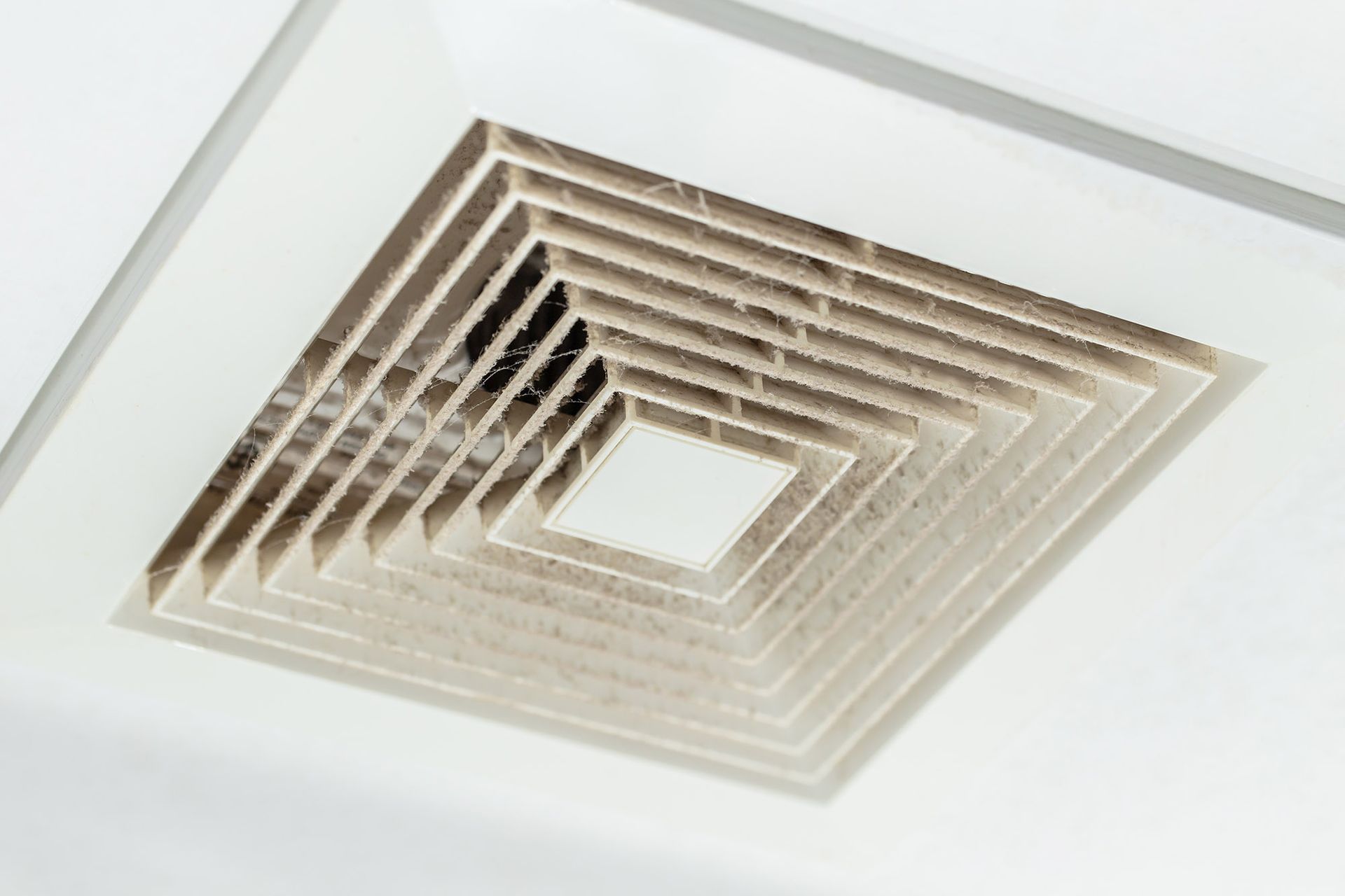 Dirty ceiling air vent in a white ceiling.