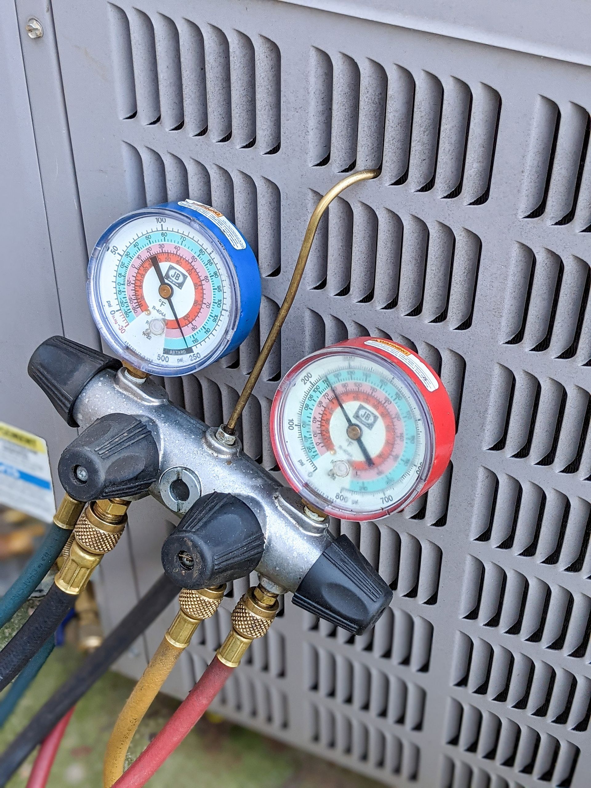A manifold gauge set connected to an air conditioning unit for servicing.