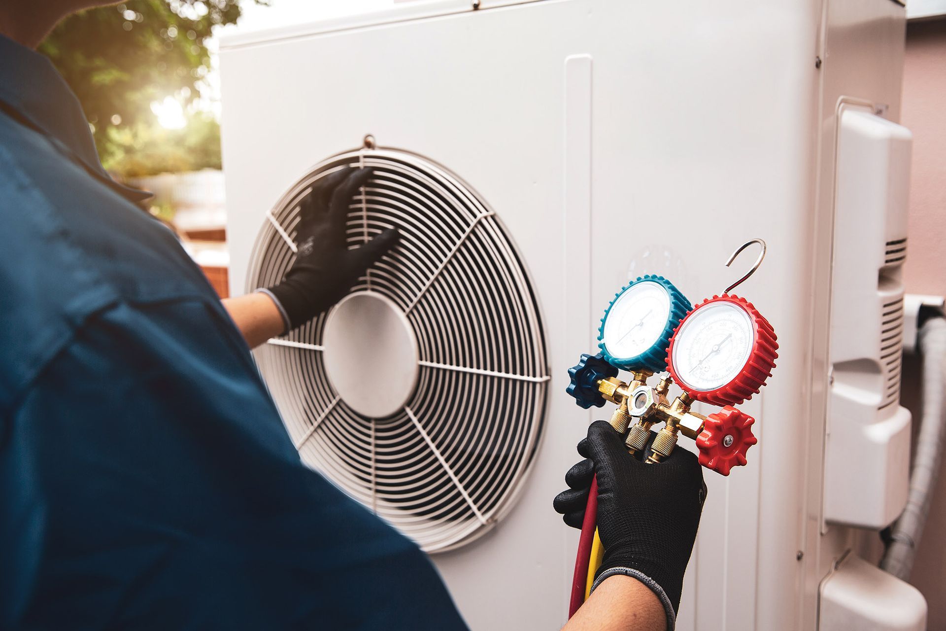 HVAC technician wearing gloves checks an air conditioner with gauges. Outdoors, close-up.