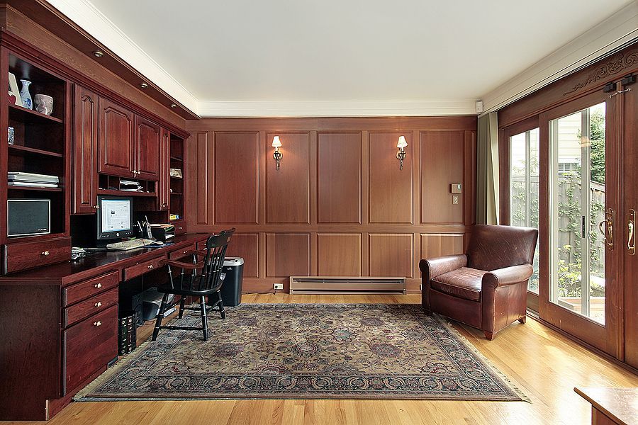 A home office with wood paneling and a rug