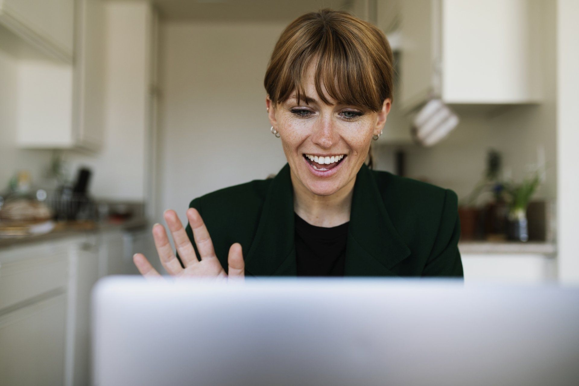 Lady waving happily at a computer.