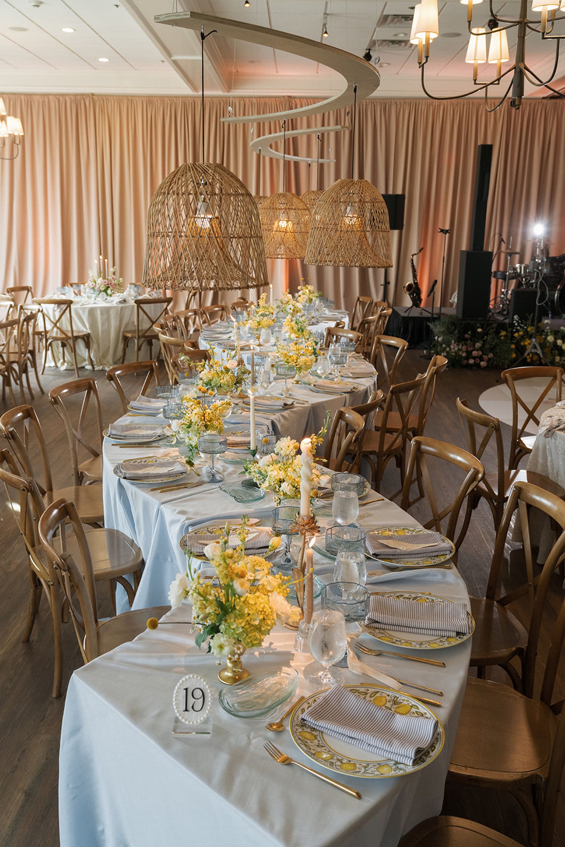 Elegant banquet table with gold chairs, white linens, and yellow floral centerpieces in a decorated hall