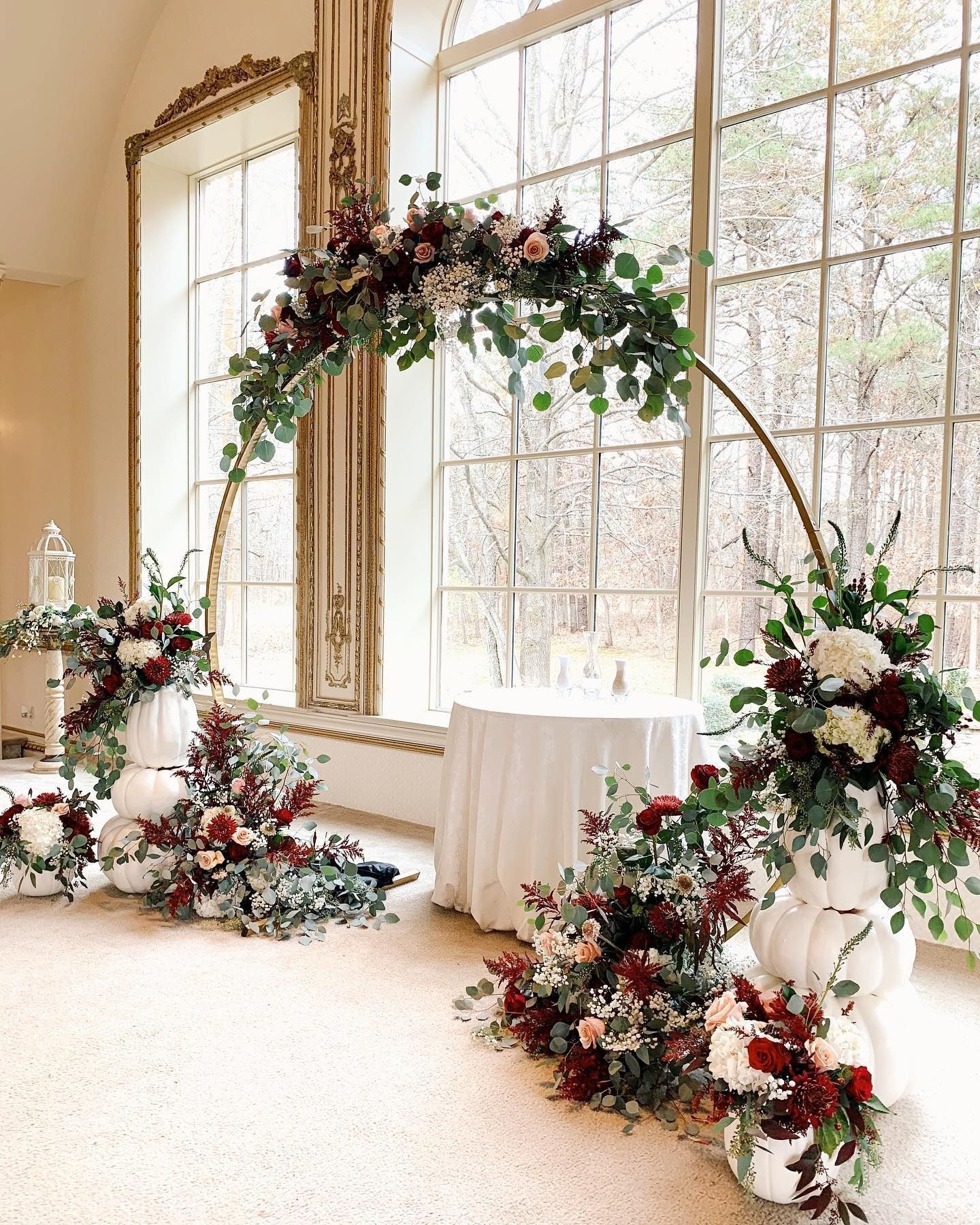 Elegant floral arch and arrangements beside large windows in a bright room