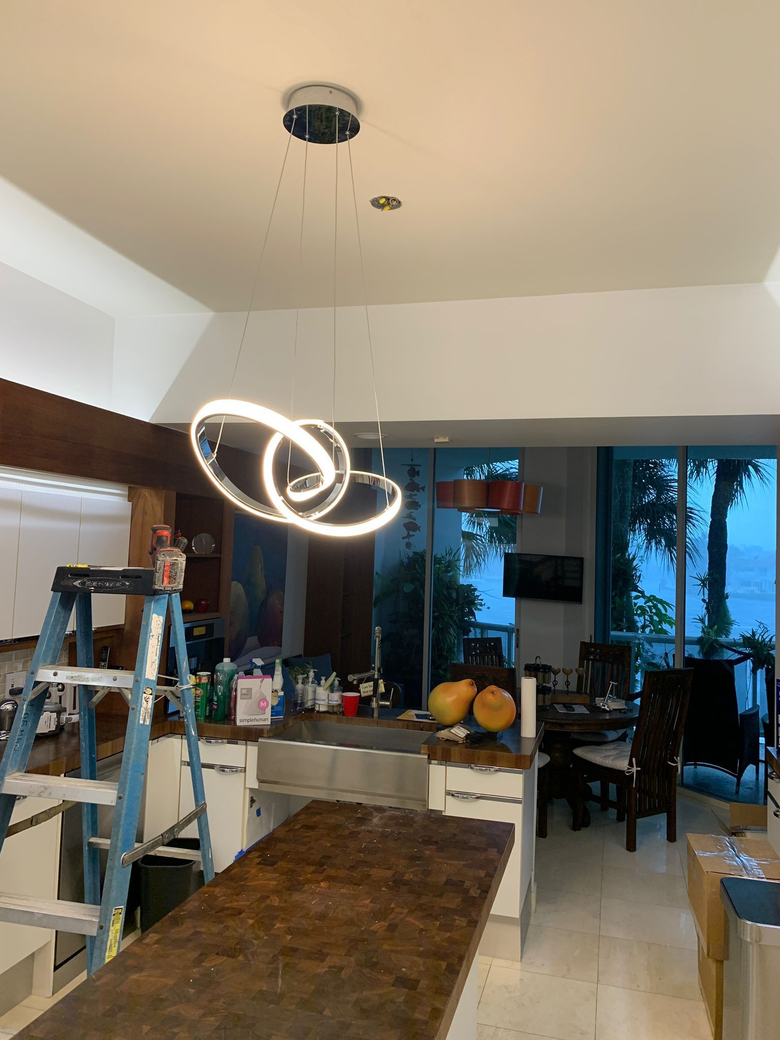 A kitchen with a ladder and a pendant light hanging from the ceiling.