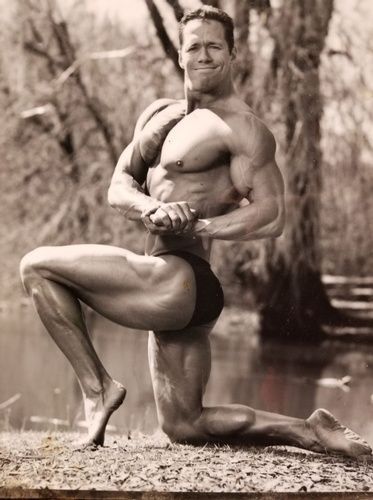 A black and white photo of a bodybuilder posing for a picture.