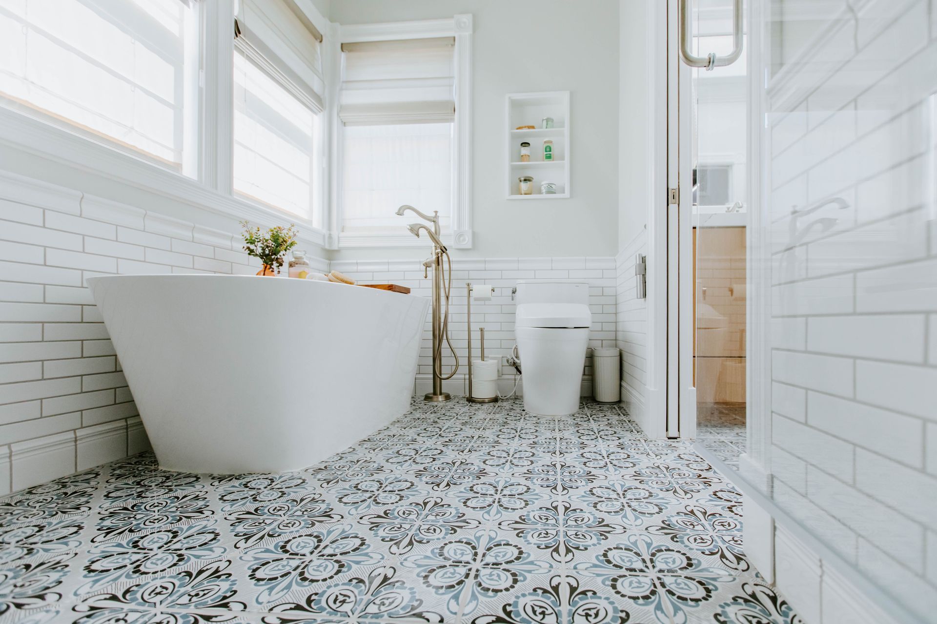 Bathroom with white bathtub, floral patterned floor tiles, and subway tile walls.