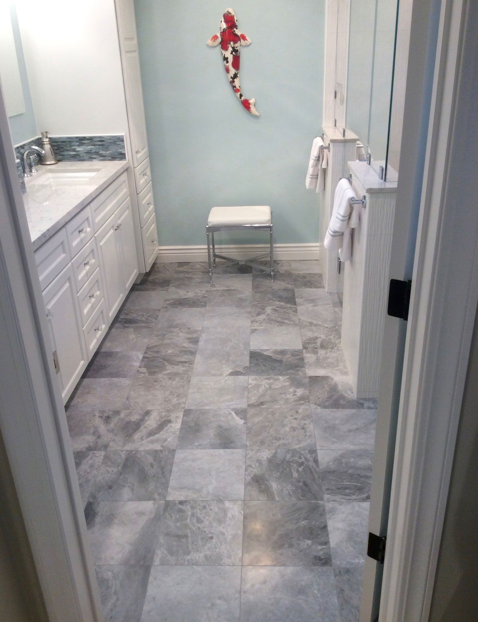 A bathroom with a tiled floor and a fish on the wall.