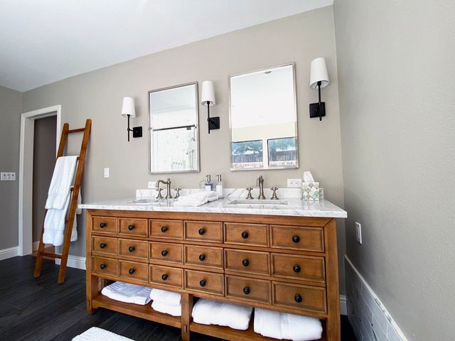 A bathroom with two sinks , two mirrors and a ladder.