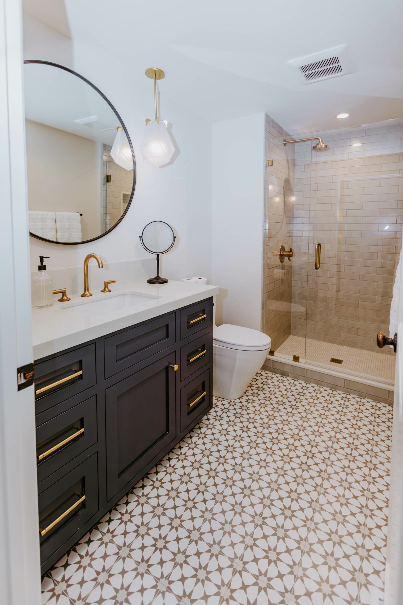 A bathroom with a toilet , sink , mirror and walk in shower.