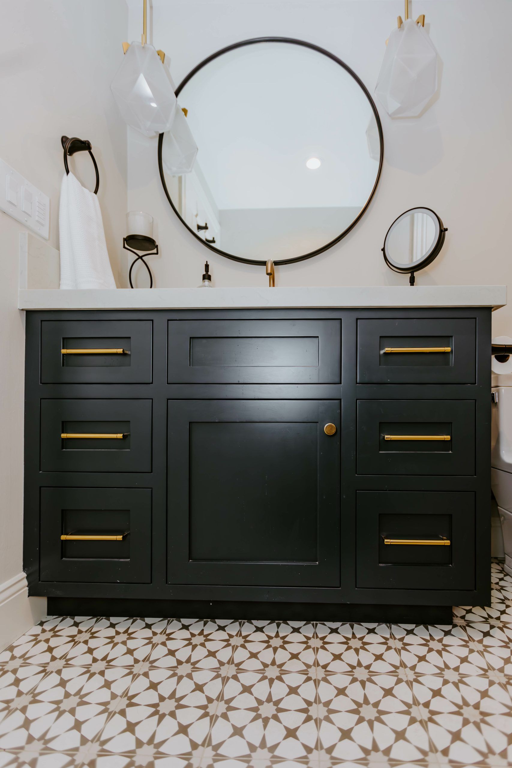 A bathroom with a black vanity and a round mirror.