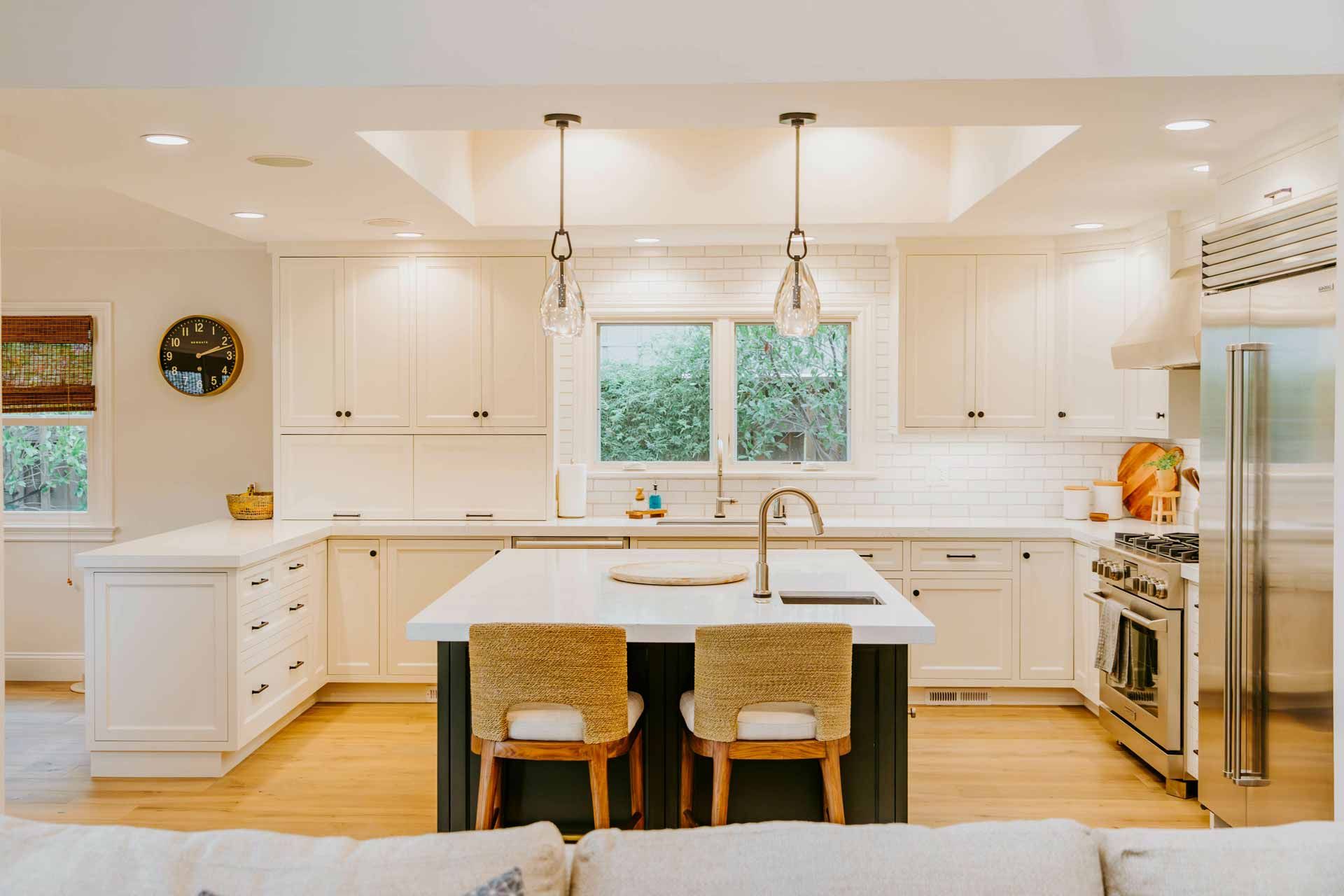 A kitchen with white cabinets , stainless steel appliances , and a large island.