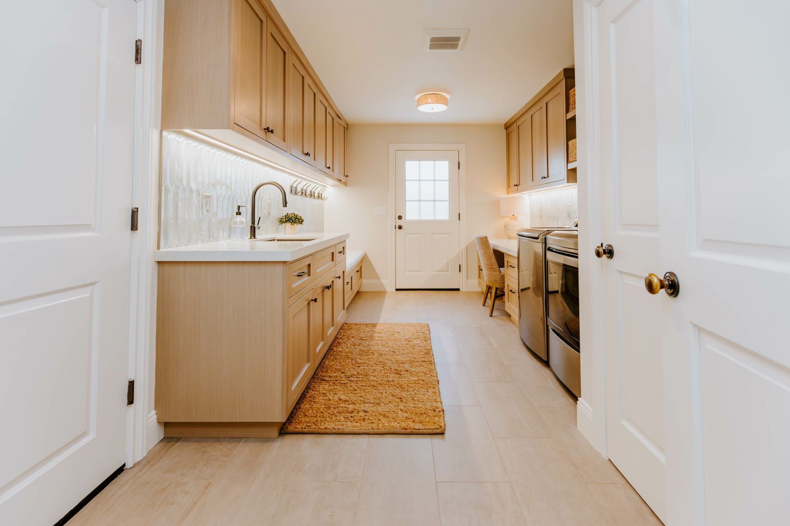 A kitchen with wooden cabinets and stainless steel appliances and a rug on the floor.