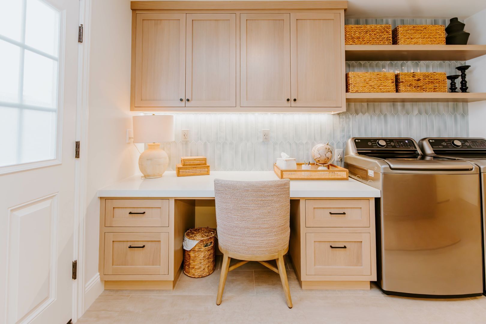 A laundry room with a desk , chair , washer and dryer.