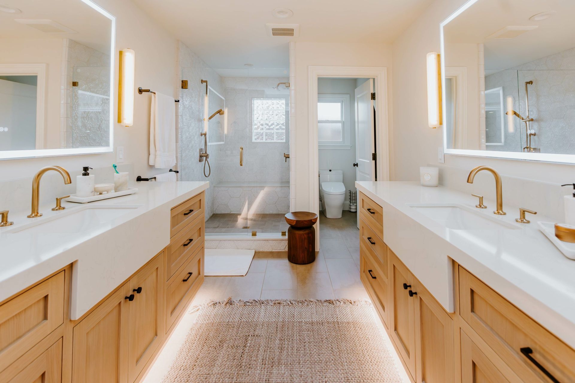 A bathroom with two sinks , two mirrors and a toilet.