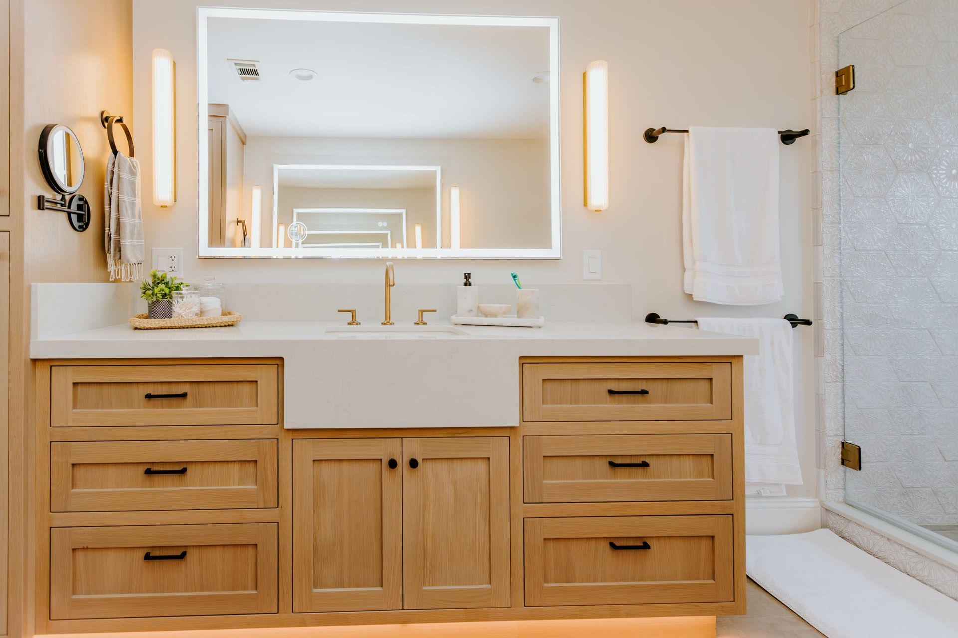 A bathroom with a sink , mirror , cabinets and drawers.