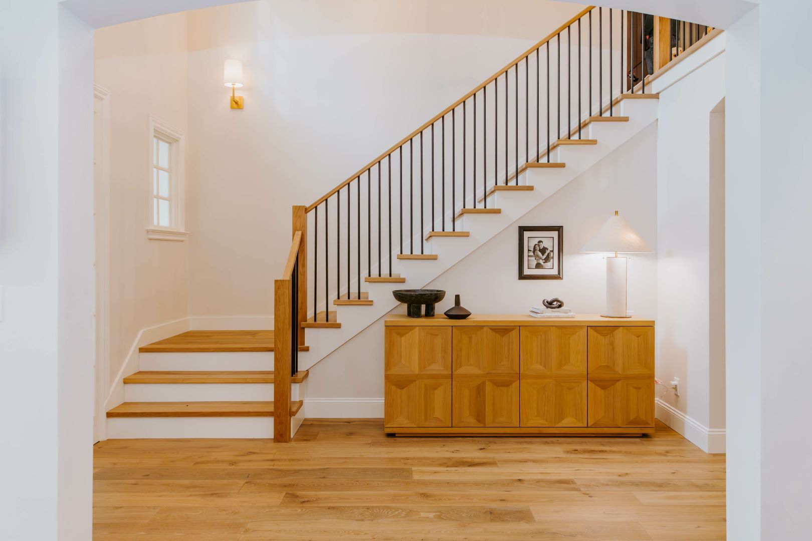 A staircase in a house with a wooden dresser underneath it.