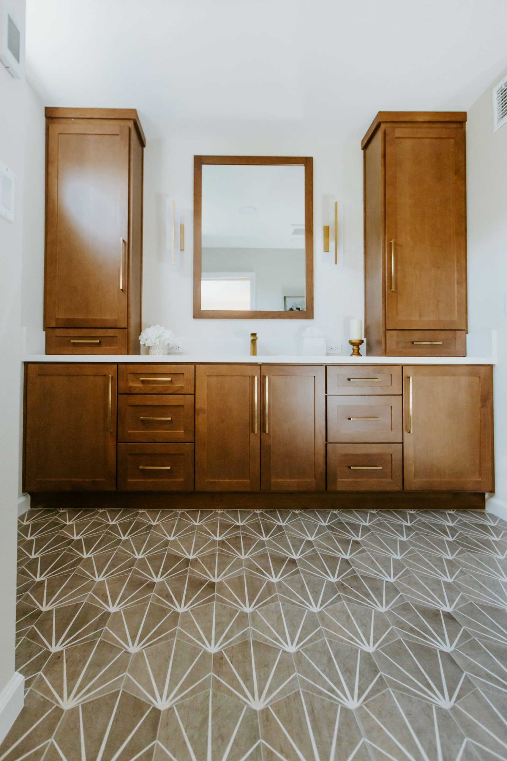 A bathroom with two sinks , a mirror , and wooden cabinets.