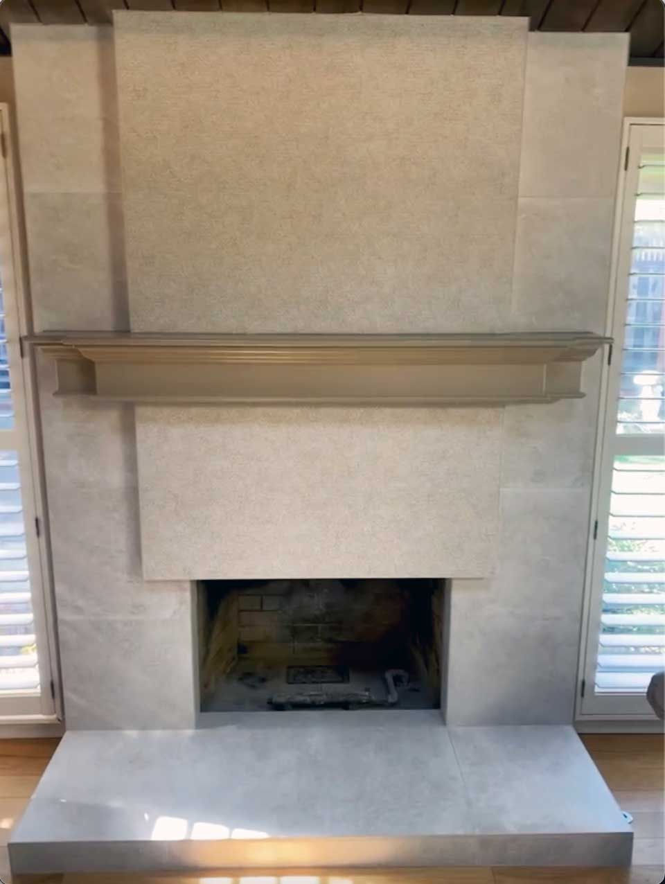 A fireplace with a mantle and shutters in a living room.