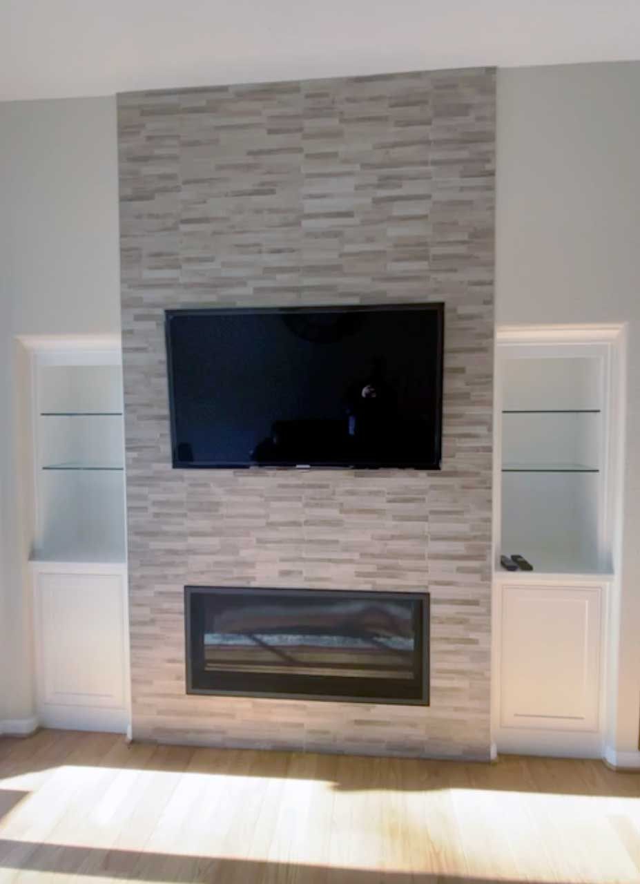 A living room with a fireplace and a flat screen tv on the wall.