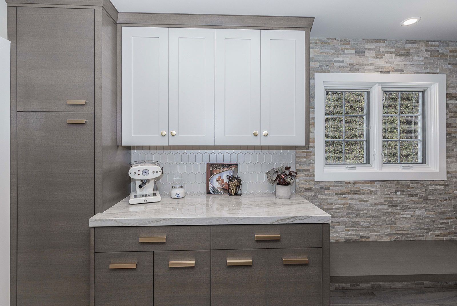 A kitchen with white cabinets and gray drawers and a window.