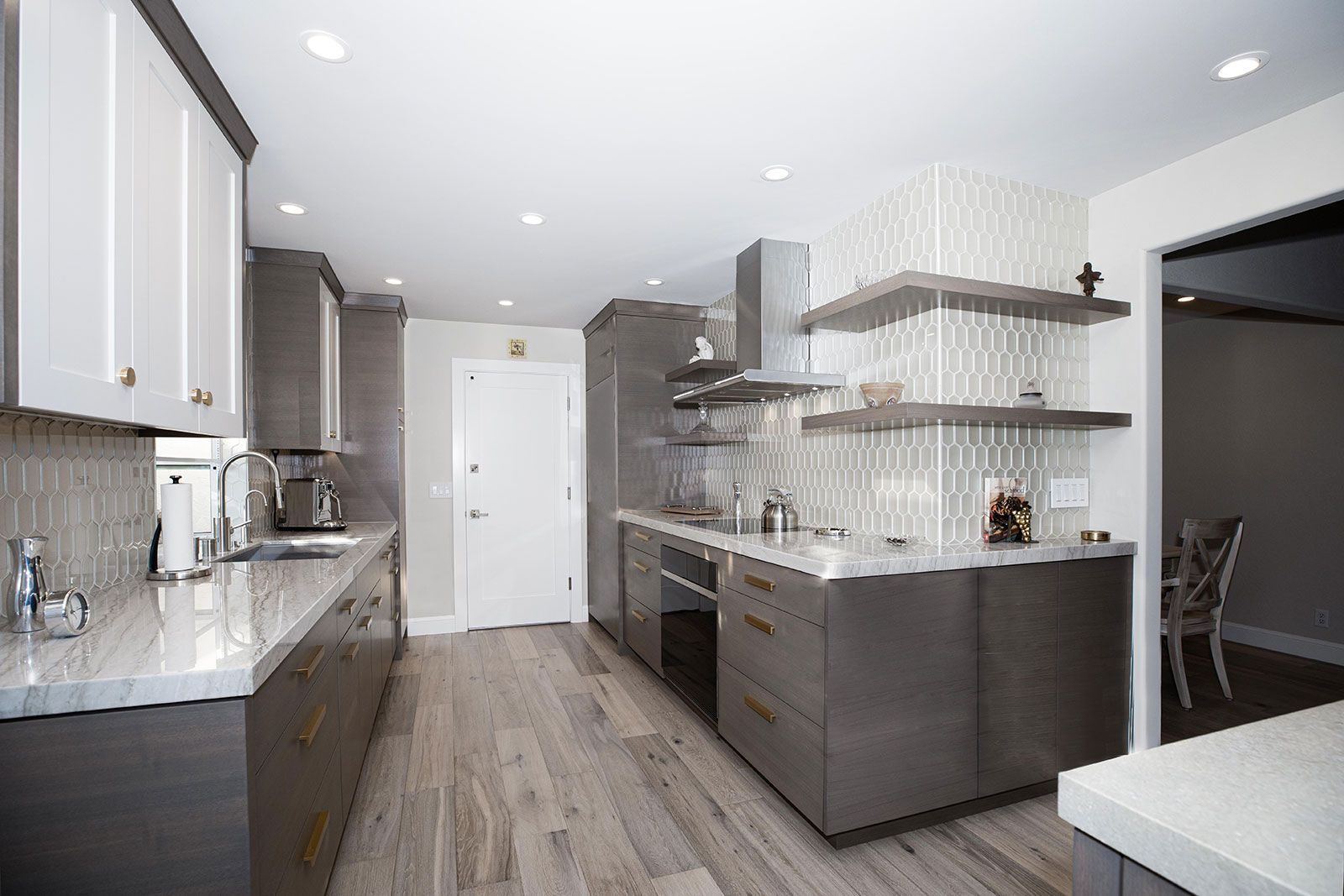 A kitchen with gray cabinets , white counter tops , and stainless steel appliances.