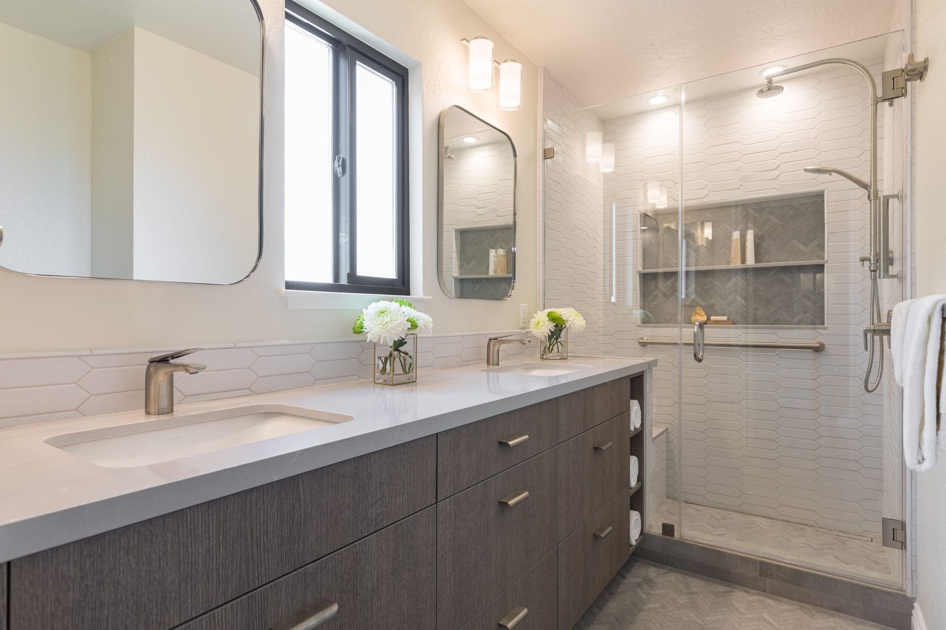 A bathroom with two sinks and a walk in shower.