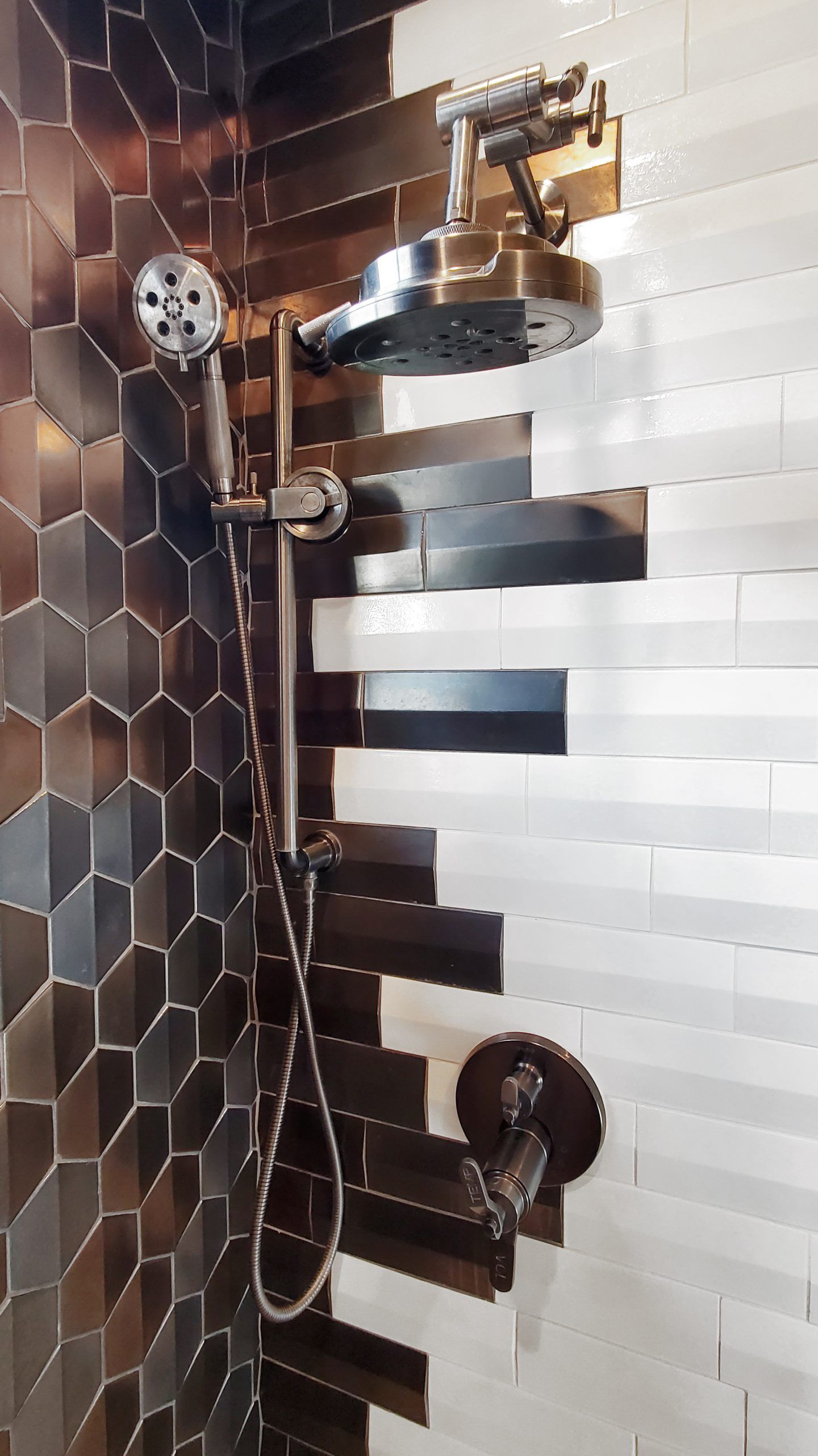 A bathroom with black and white tiles and a shower head.