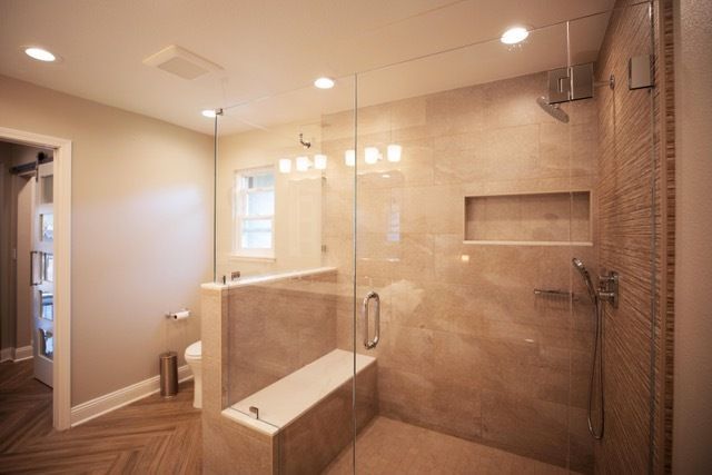 A bathroom with a walk in shower and a bench.