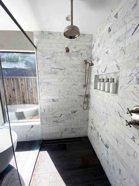 A bathroom with marble walls and a walk in shower