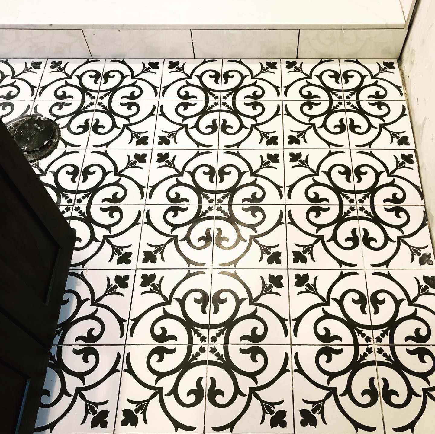A black and white tile floor with a floral pattern