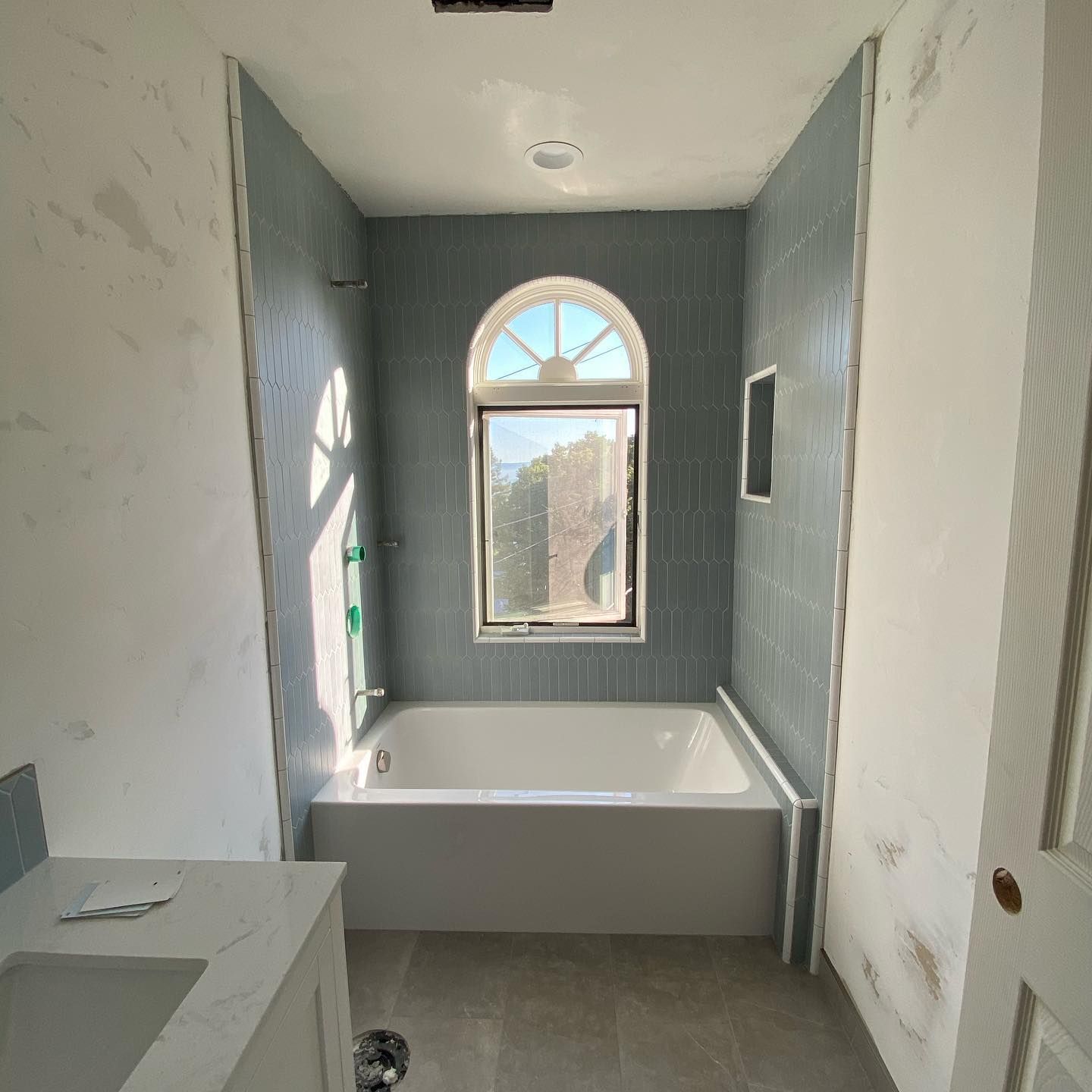A bathroom with a tub , sink , and window.