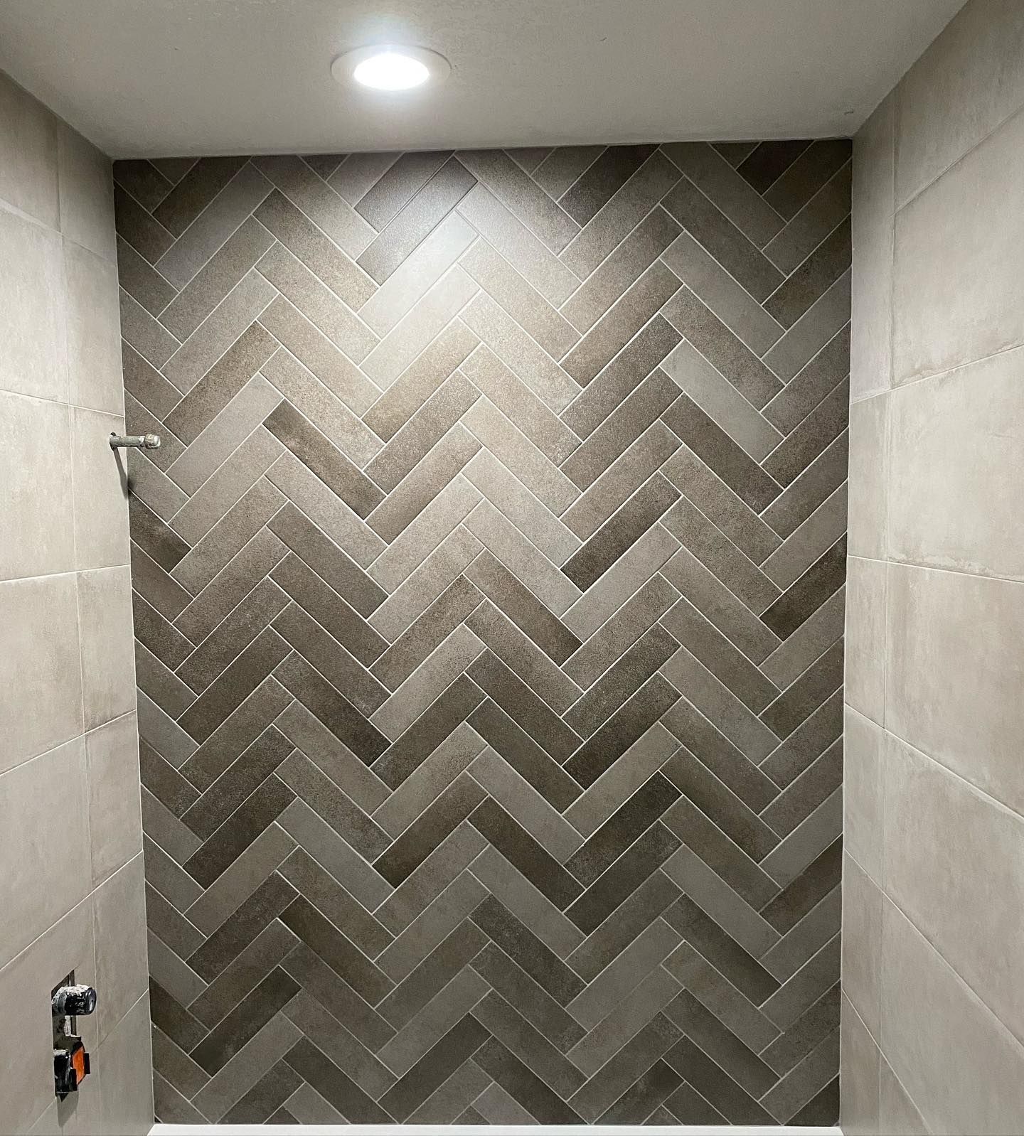 A shower with a herringbone pattern on the wall