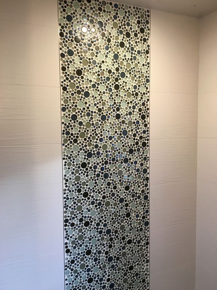 A wall with a mosaic tile pattern on it in a bathroom.