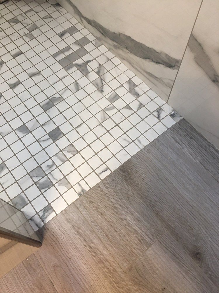 A bathroom floor with marble tiles and a wooden floor.