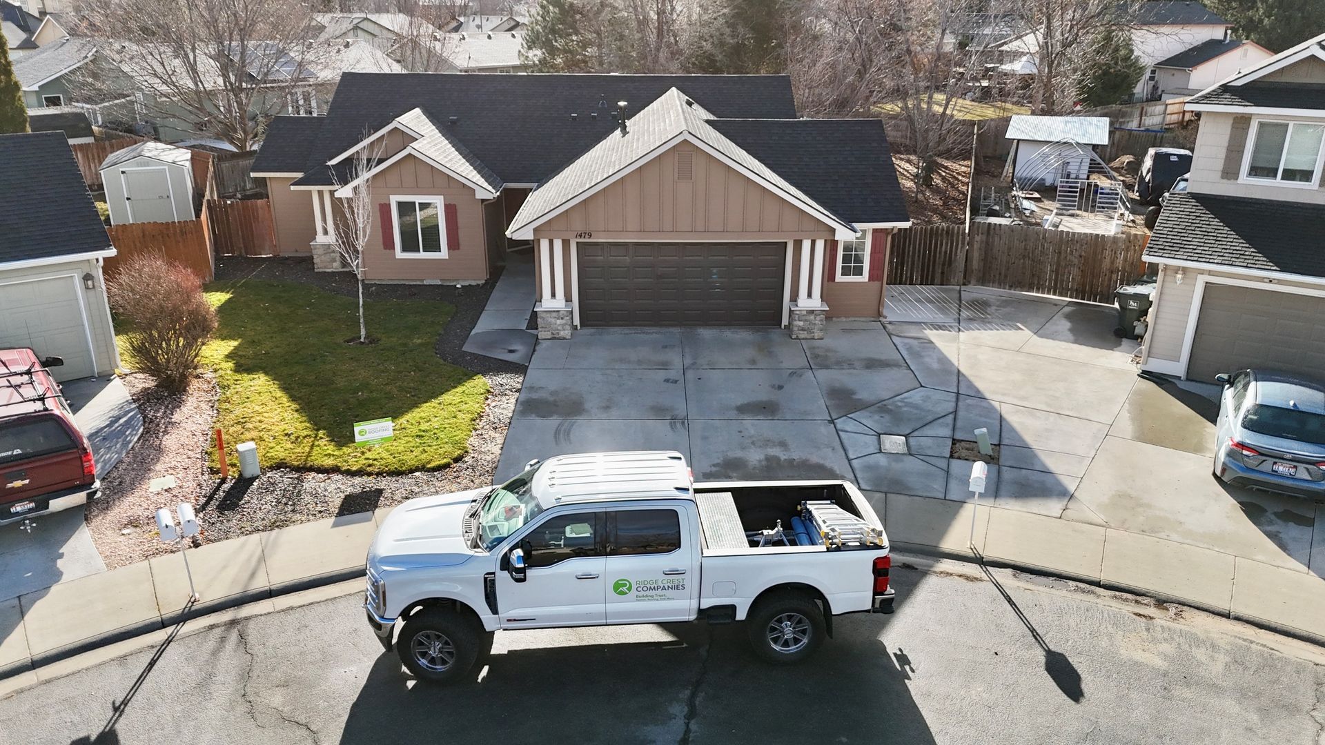 White service truck in a driveway in front of a brown house.