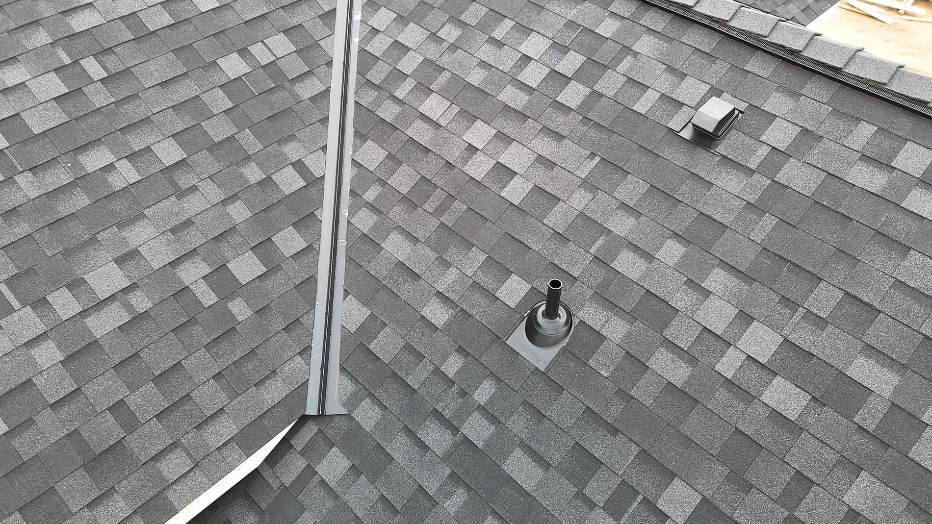 Dark gray asphalt shingle roof with a vent and a chimney.