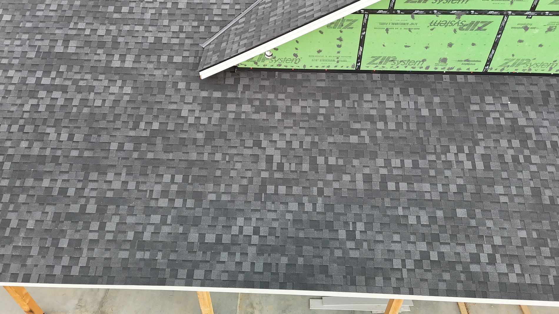 Dark gray shingle roof of a building with visible wooden frame.