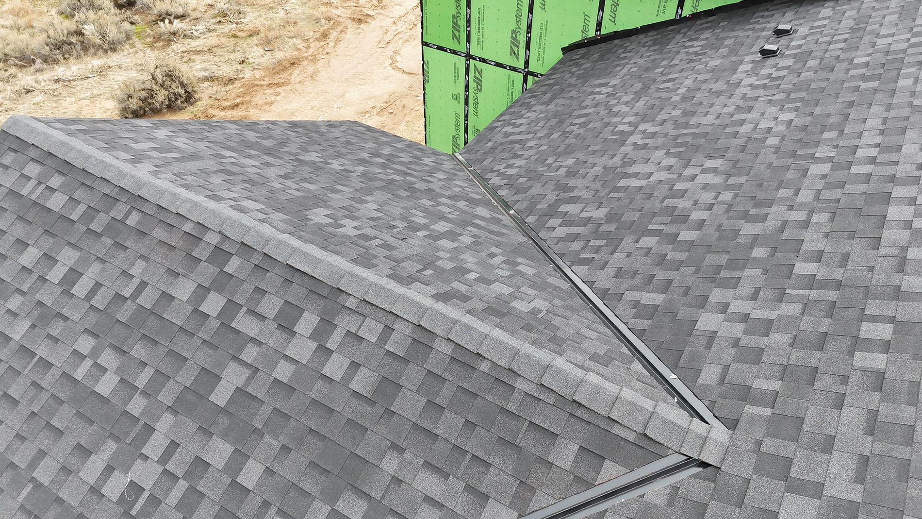 Overhead view of a gray shingled roof with a dark gray ridge.