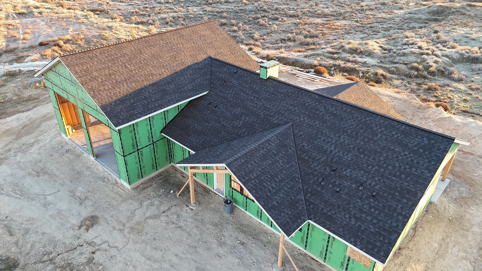 New house under construction with dark roof and green siding.