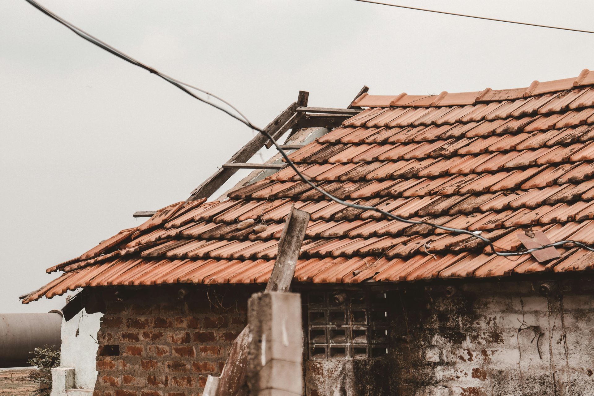Old rural house with a weathered red tile roof and overhead power lines