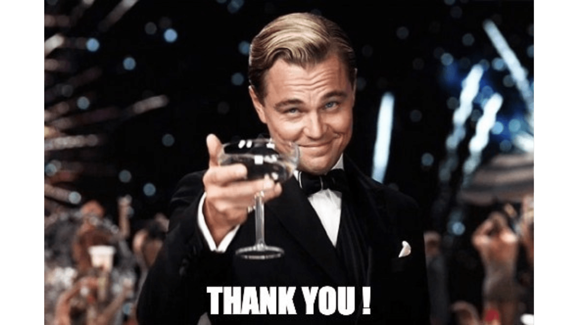 A man in a tuxedo is holding a glass of wine and saying thank you.