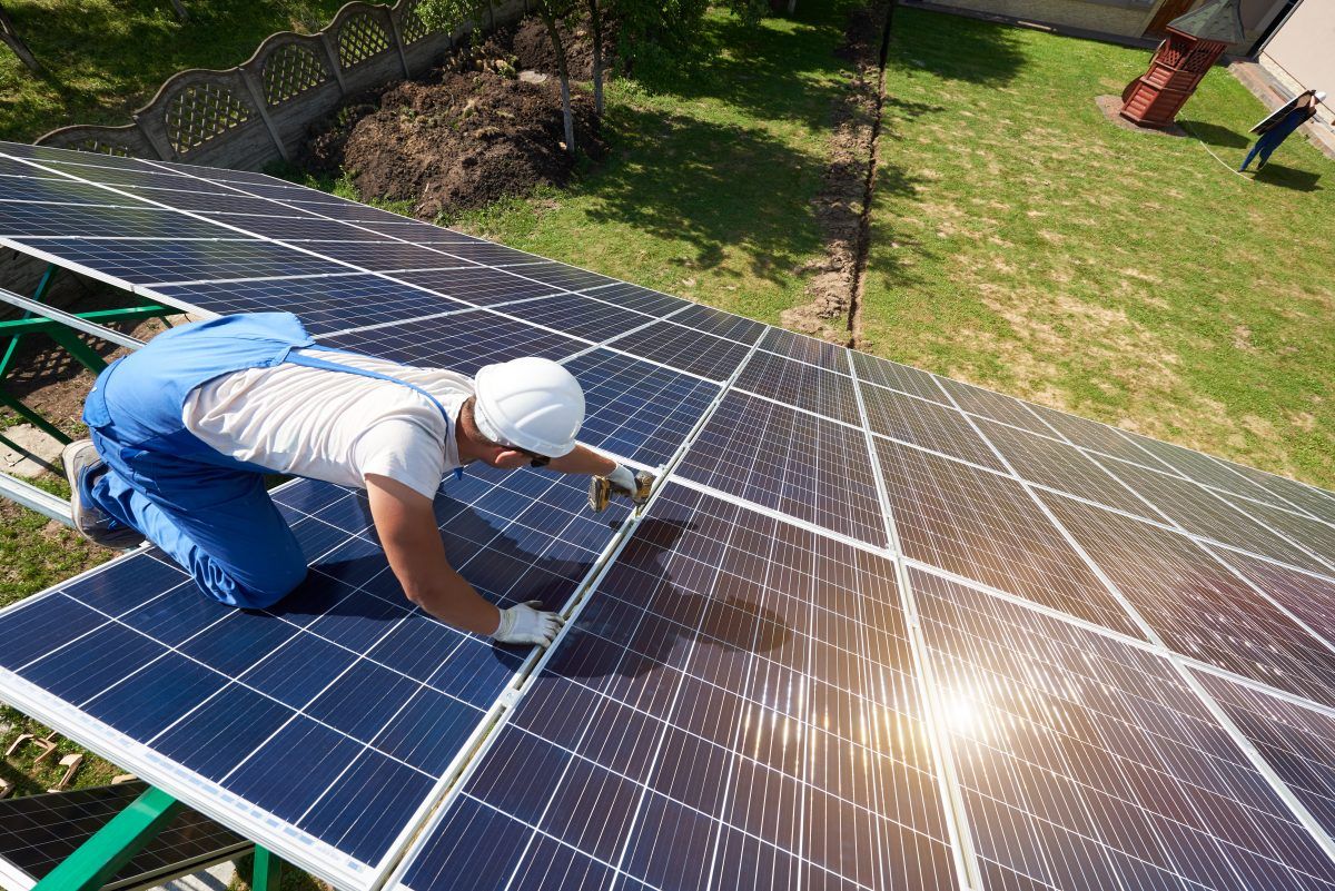 A man is installing solar panels on a roof.