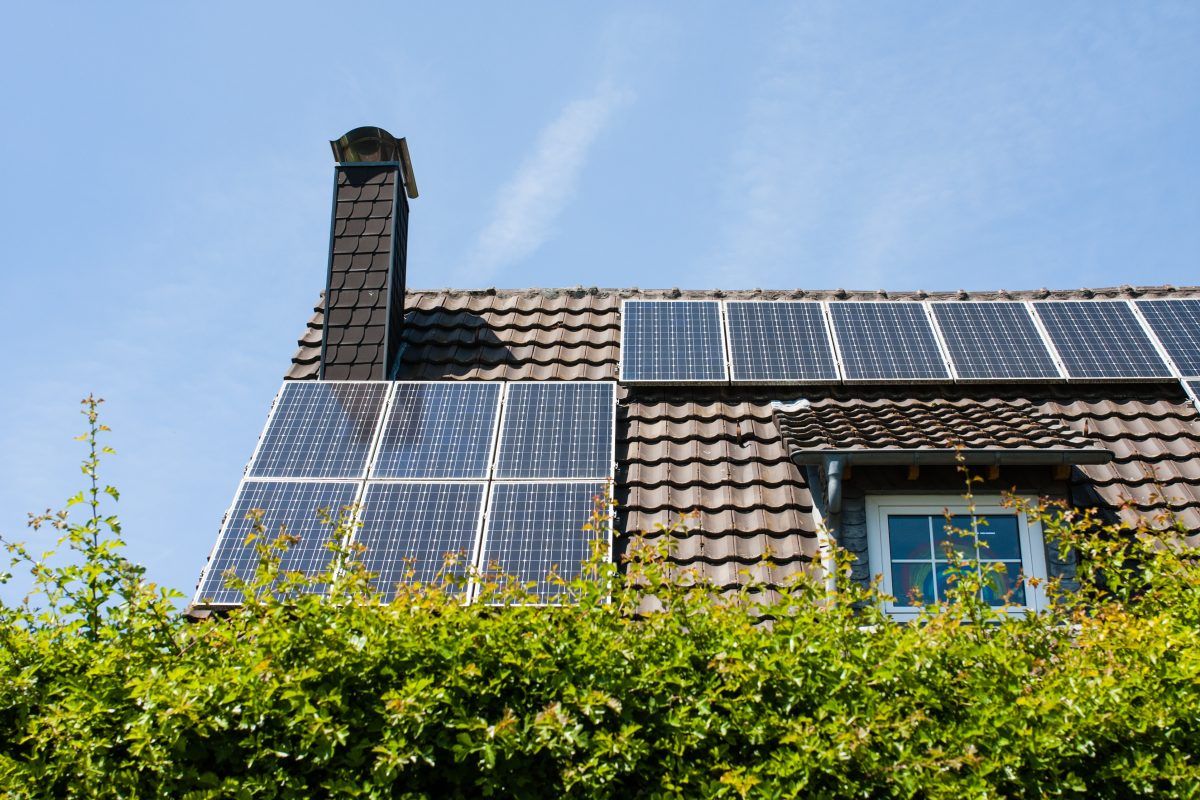 A house with solar panels on the roof and a chimney.