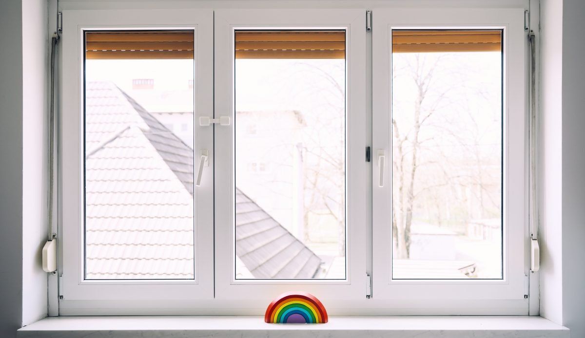 A rainbow is sitting on a window sill next to a window.
