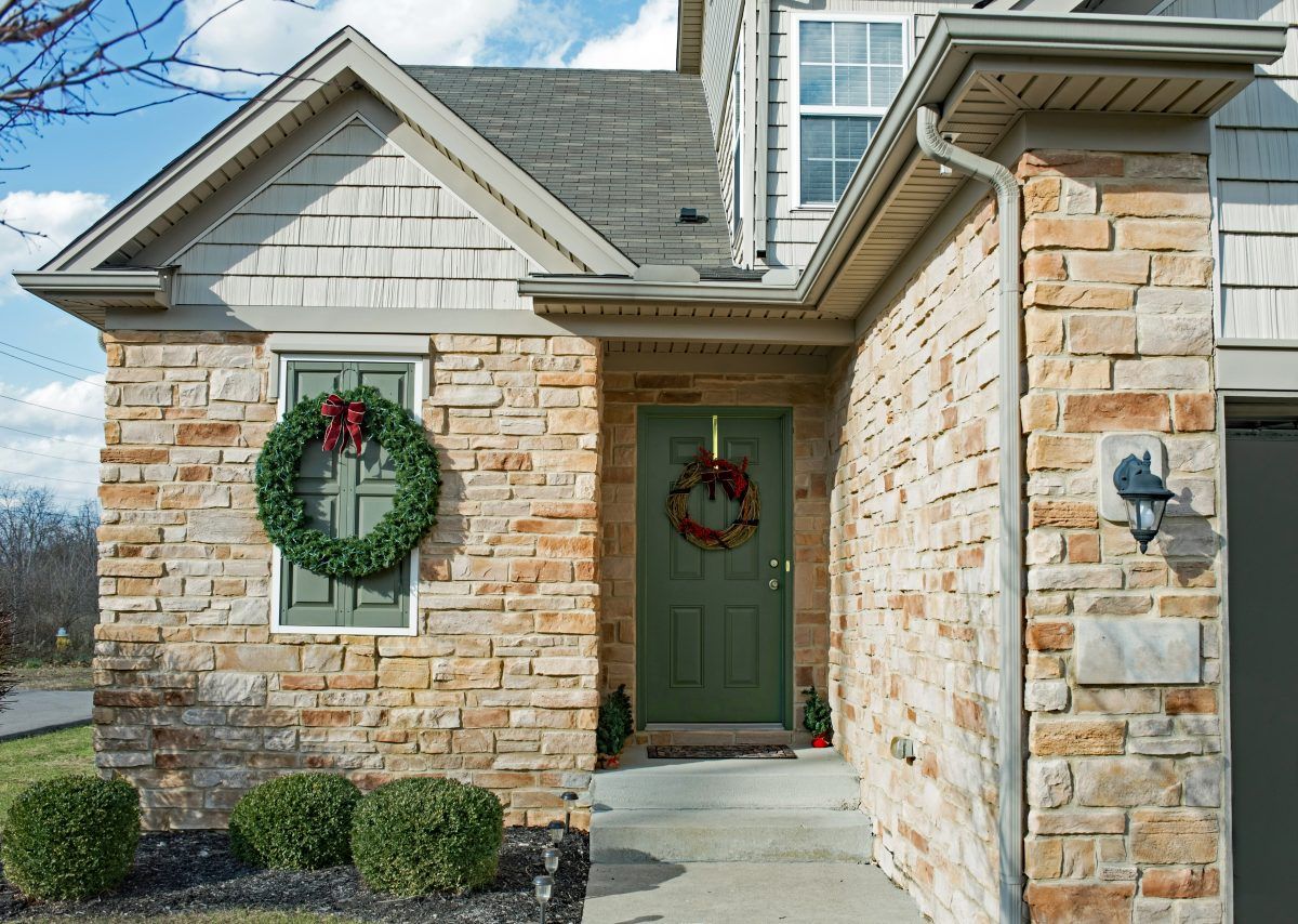 A brick house with a green door and a wreath on the door