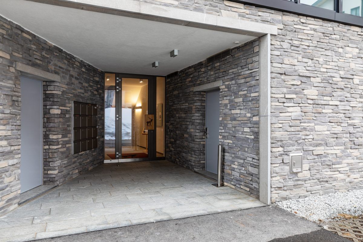 The entrance to a building with a stone wall and a glass door.