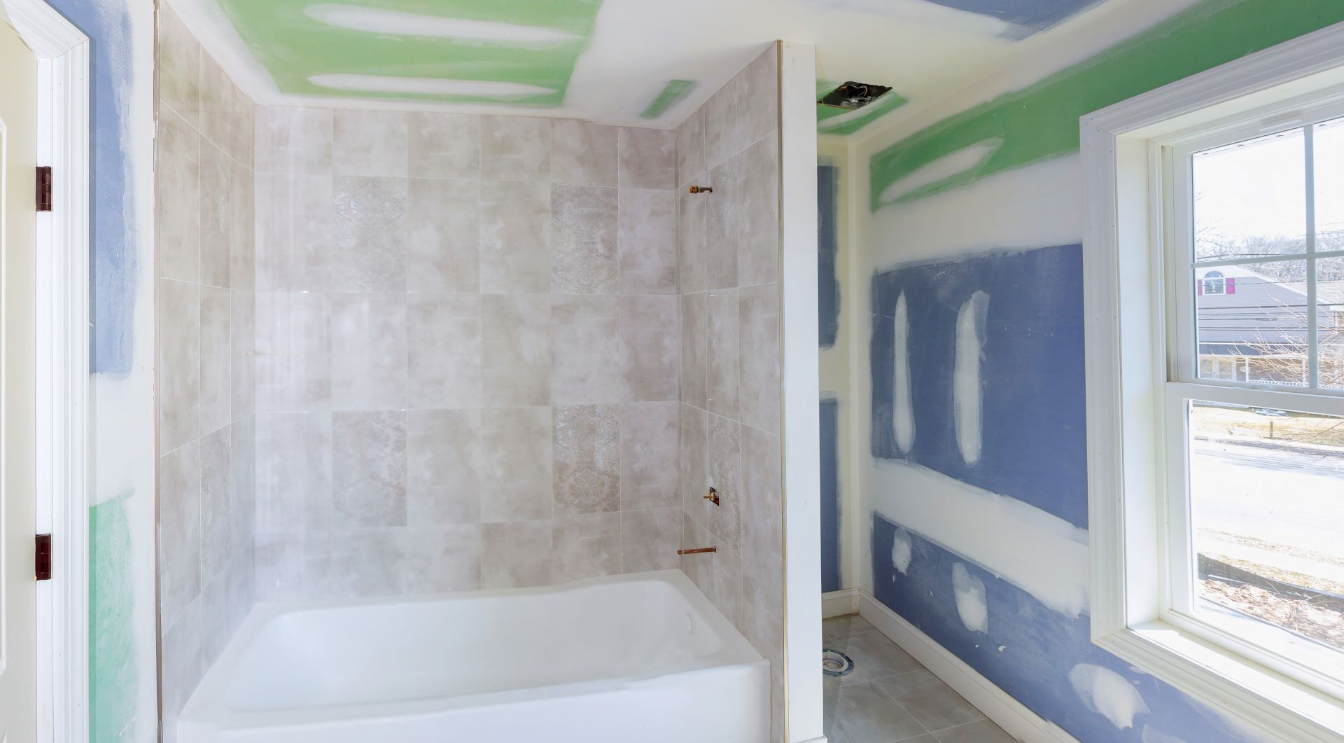 Bathroom remodel progresses as drywall is smoothed, covering seams and screws with tape and spackle mud