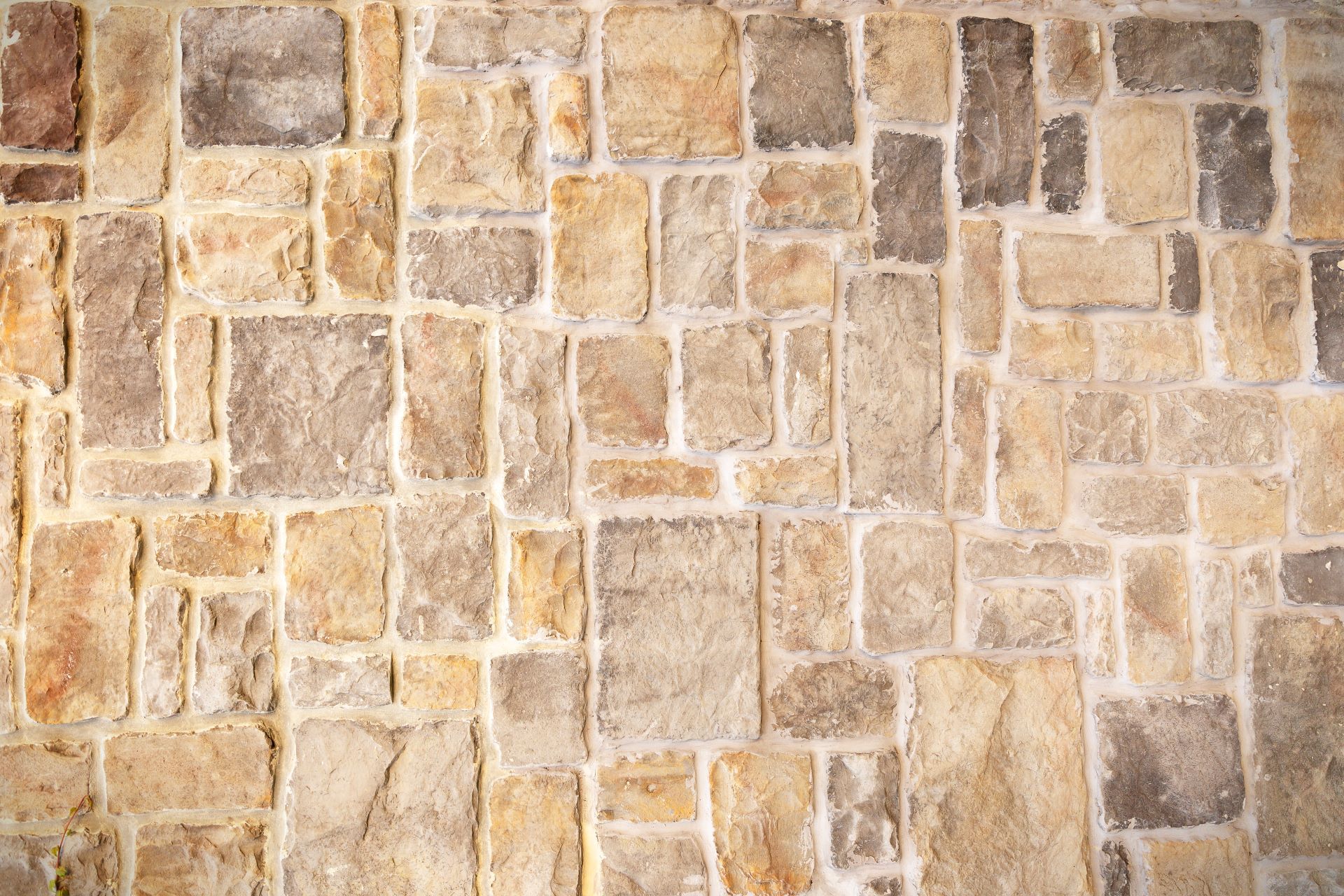Light stone tiles lying diagonally. A stone wall.